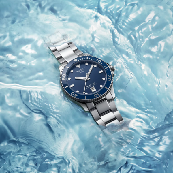 A silver wristwatch with a blue dial on icy surface.