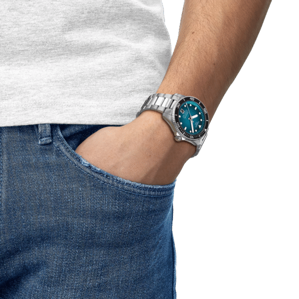 Person wearing blue jeans and a wristwatch with hand in pocket.
