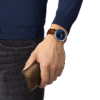 Hand wearing a blue-faced watch holding a brown leather wallet.