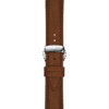 Close-up of a brown leather watch strap with a silver buckle on a matching brown background.