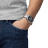 Man wearing a silver wristwatch with hand in jeans pocket.