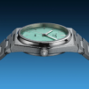 Close-up of a silver wristwatch with a mint green face against a blue background.